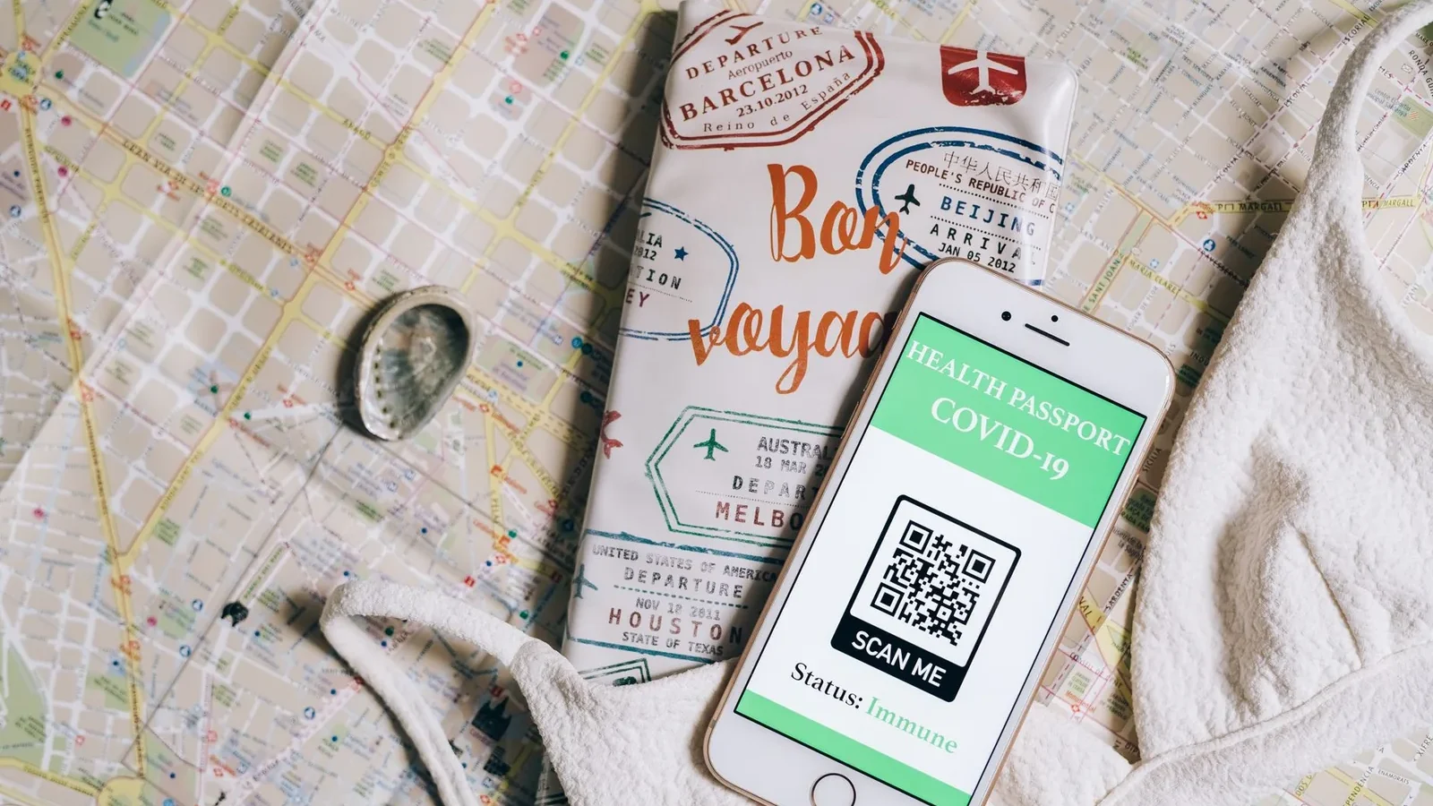 Smartphone displaying a health passport with QR code on a travel map and passport cover.
