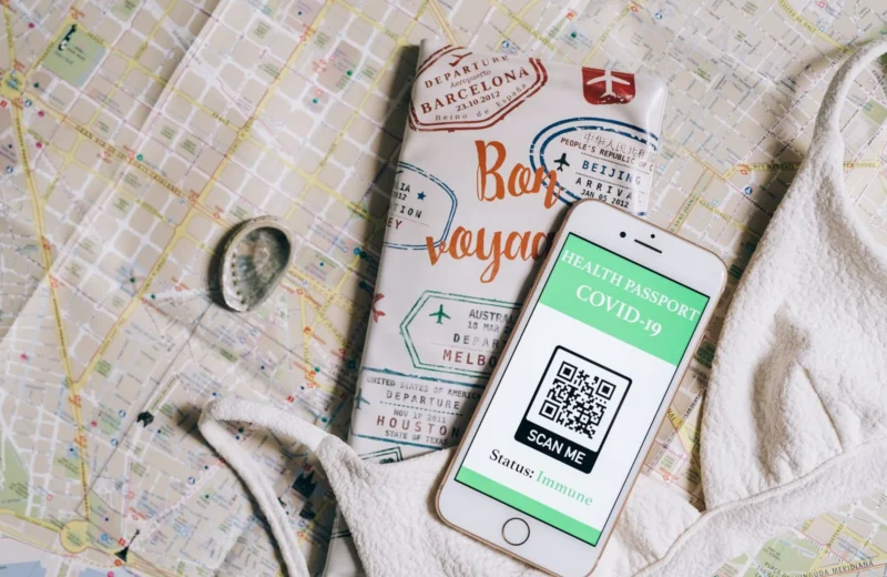 Smartphone displaying a health passport with QR code on a travel map and passport cover.