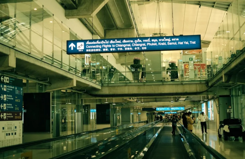 View of Suvarnabhumi Airport interior with moving walkway and signs for connecting flights.