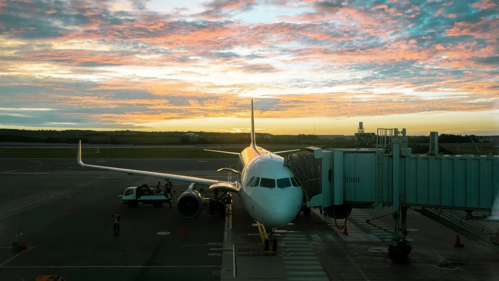 A plane at Makung Airport during a stunning sunset, reflecting vibrant skies.