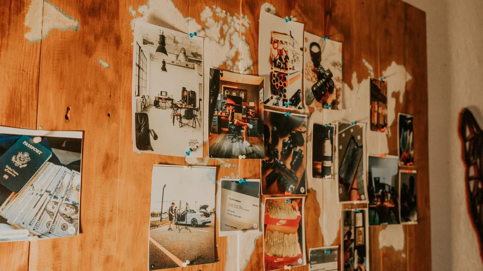 A collection of travel photos pinned on a wooden map-themed wall, evoking adventure and nostalgia.