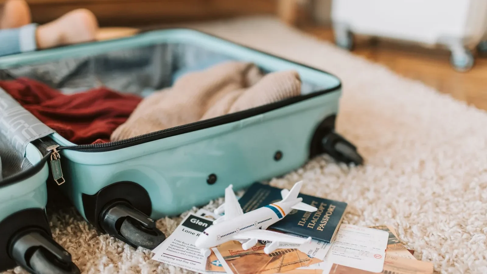 Close-up of an open suitcase with travel essentials like passport and tickets, ready for a journey.