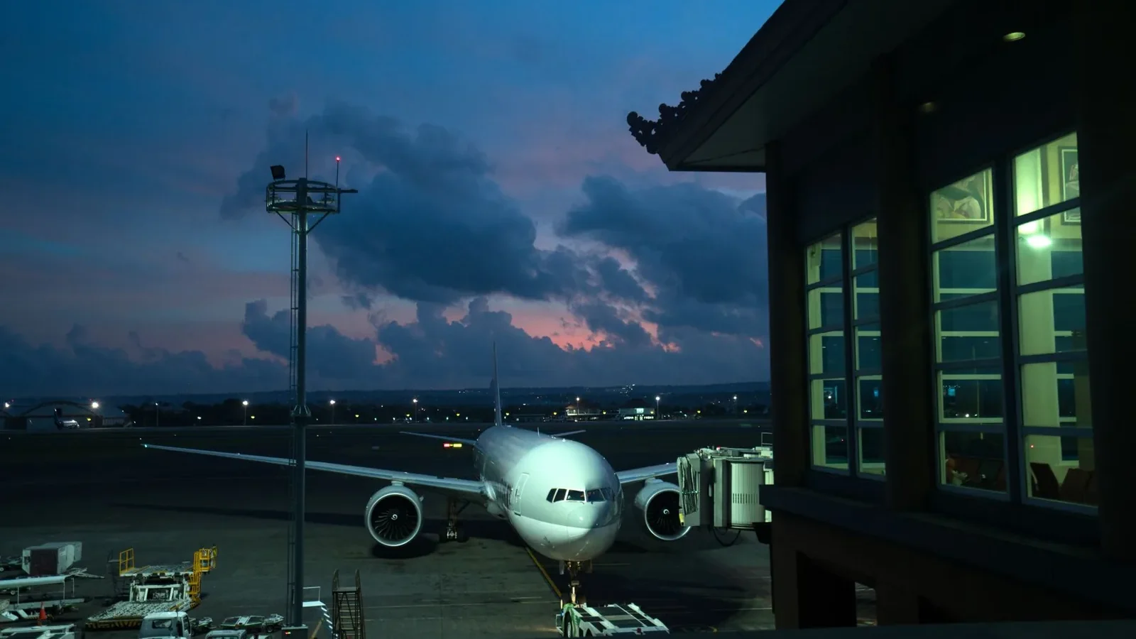 Contemporary aircraft located near airbridge on modern airport airfield against scenic dusk sky.