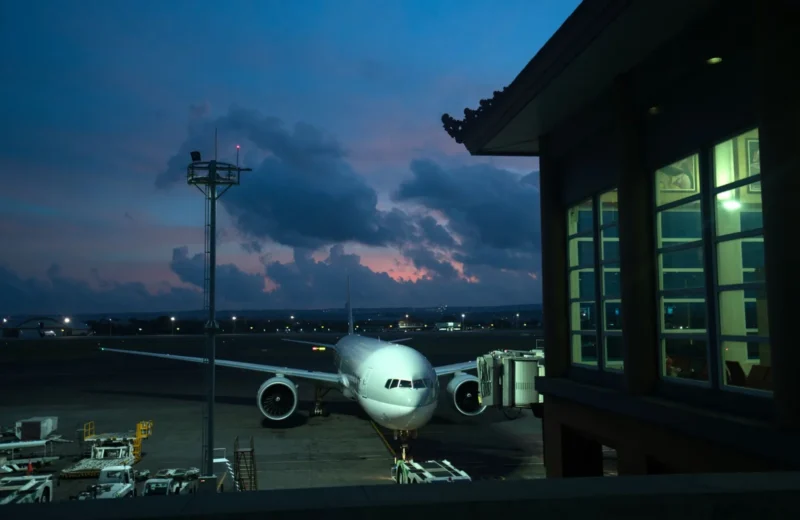 Contemporary aircraft located near airbridge on modern airport airfield against scenic dusk sky.