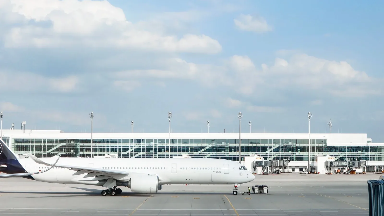Widebody aircraft parked at an airport gate during clear day with terminal building visible.