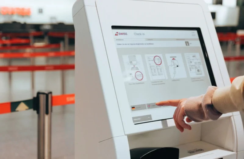Passenger using self-service check-in kiosk at airport for convenient travel experience.