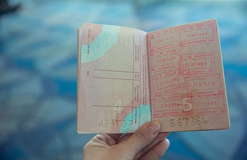 Close-up view of an open passport displaying various travel stamps in an airport setting.