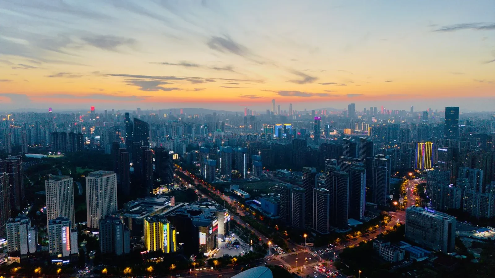 Stunning aerial view of a bustling city skyline at sunset, vibrant lights illuminate the urban landscape.