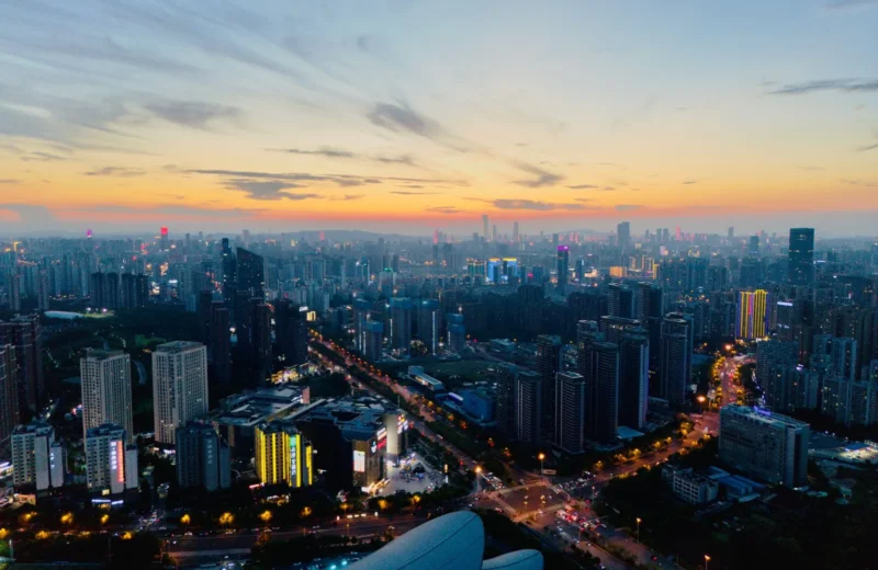 Stunning aerial view of a bustling city skyline at sunset, vibrant lights illuminate the urban landscape.