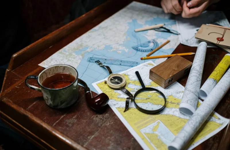 Overhead view of navigation tools with maps, compass, and coffee cup.