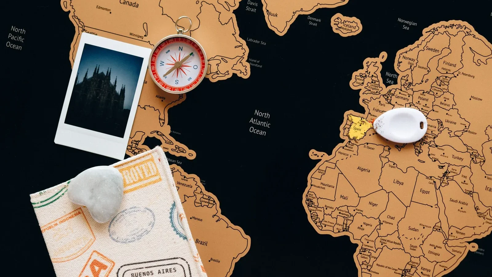 Flat lay of travel items including a map, compass, and polaroid for adventure planning.
