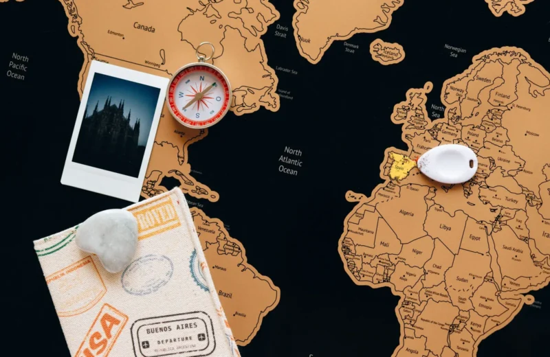 Flat lay of travel items including a map, compass, and polaroid for adventure planning.