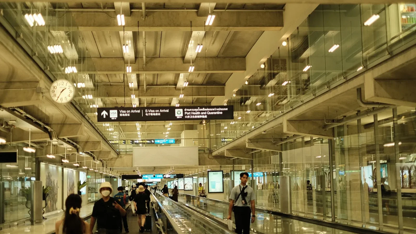 Passengers walking in a well-lit modern airport terminal with glass design.