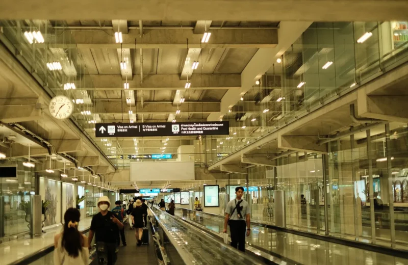 Passengers walking in a well-lit modern airport terminal with glass design.