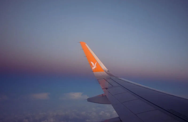 A serene view of an airplane wing soaring over clouds during sunset.