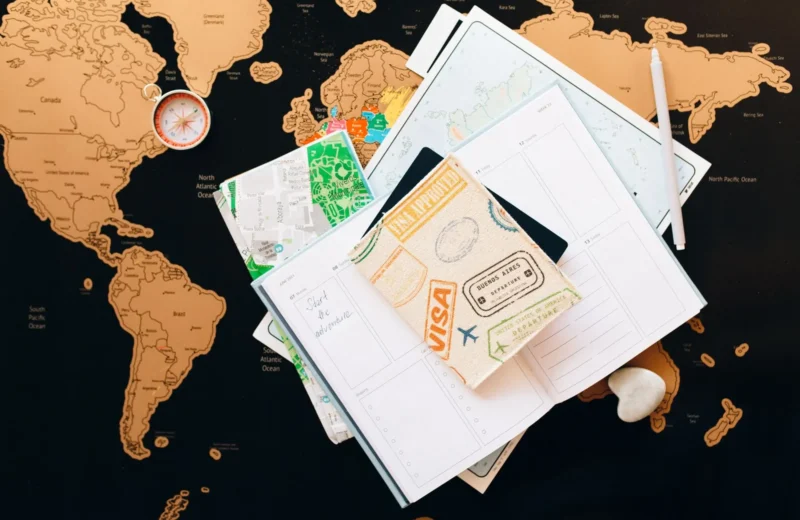 A flat lay of travel planning items on a map, featuring a compass, notebook, and guide for wanderlust enthusiasts.