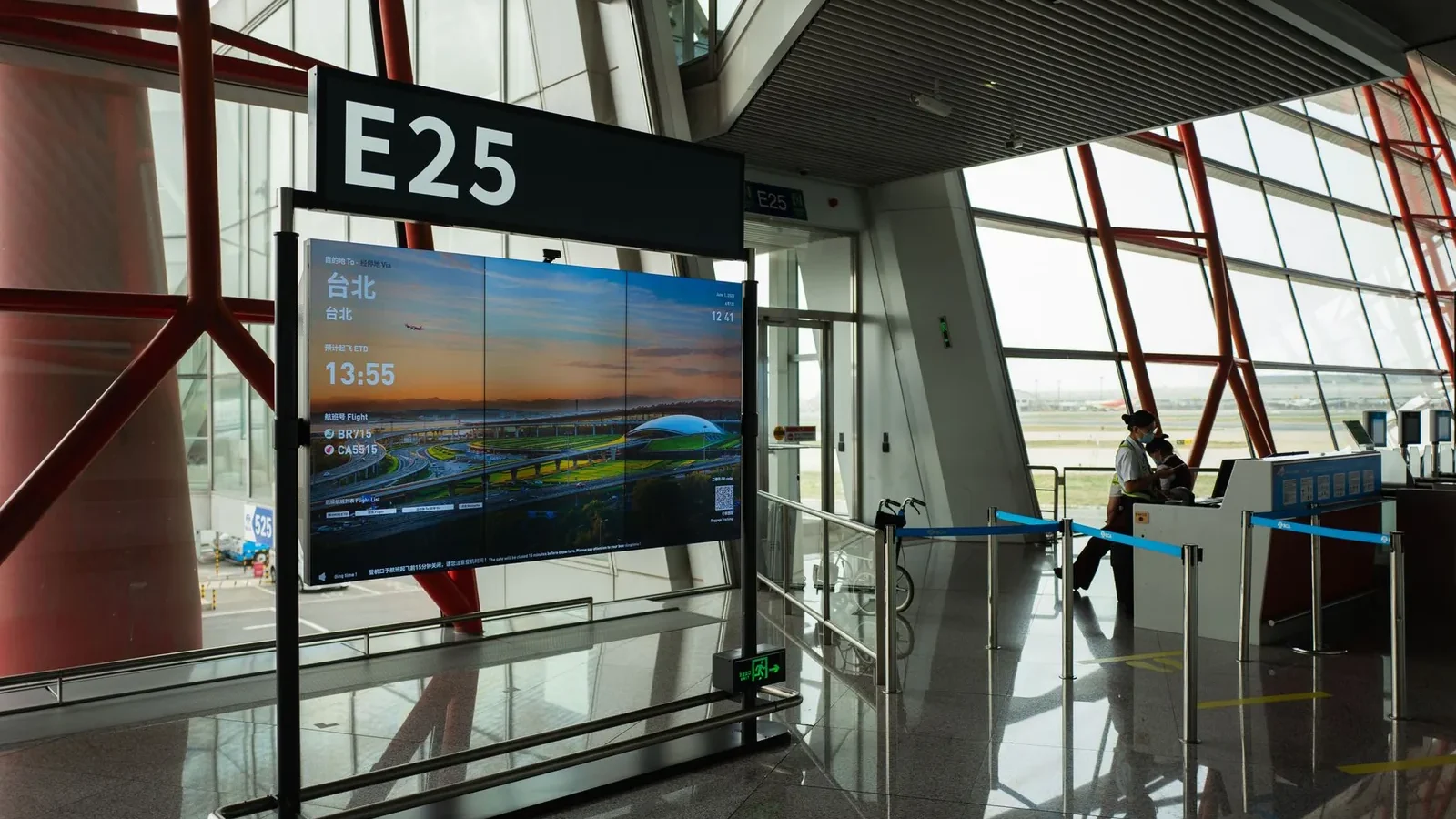 A view of a modern airport terminal showcasing Gate E25 with a flight display board.