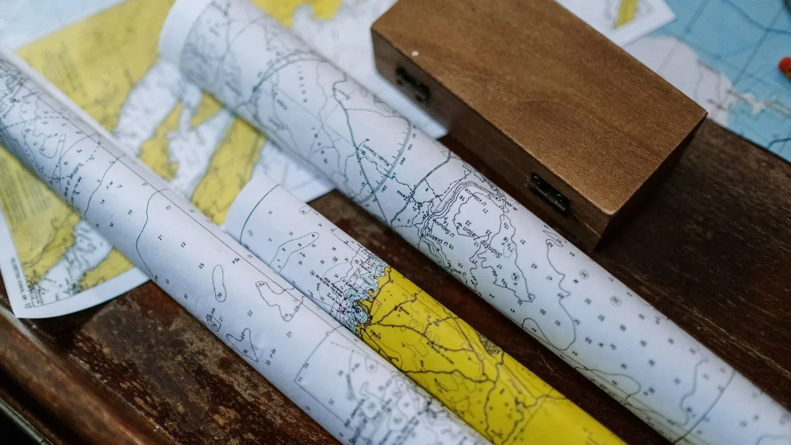 Close-up of rolled nautical maps on a wooden table, perfect for navigation themes.