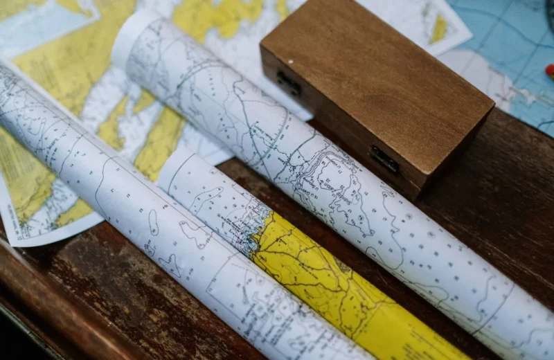 Close-up of rolled nautical maps on a wooden table, perfect for navigation themes.