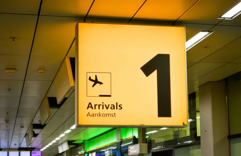 Bright arrivals sign with airplane symbol in an airport terminal.