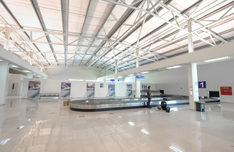 A modern and empty airport baggage claim area with a traveler waiting.