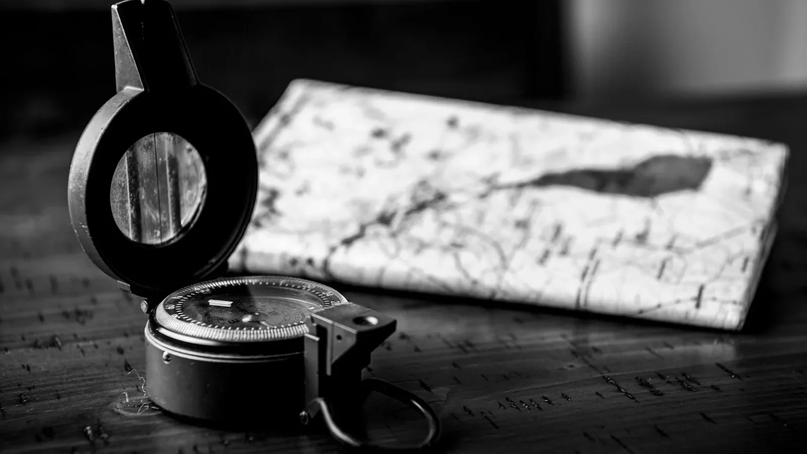 Monochrome close-up of a vintage compass and map, symbolizing navigation and exploration.