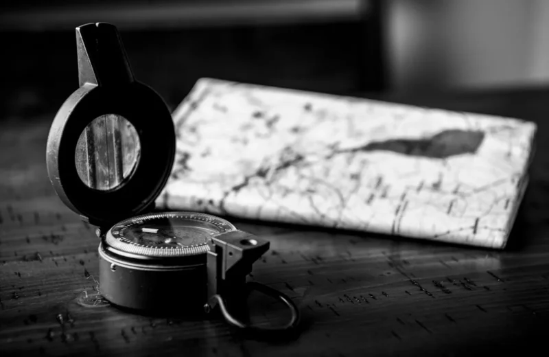 Monochrome close-up of a vintage compass and map, symbolizing navigation and exploration.