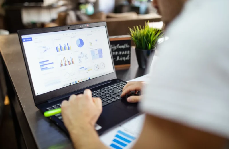 Focused business analysis with charts and graphs on a laptop in a modern office setting.