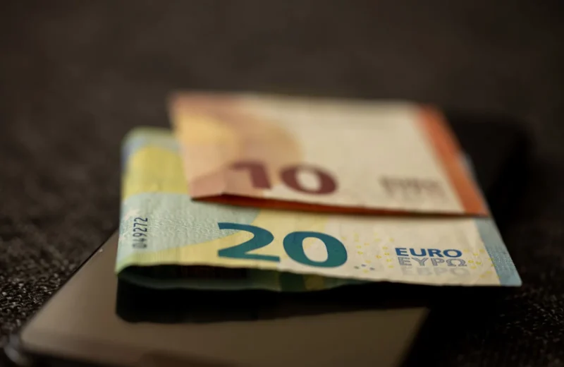 A detailed close-up shot of 10 and 20 euro banknotes placed on a smartphone, representing finance and technology.
