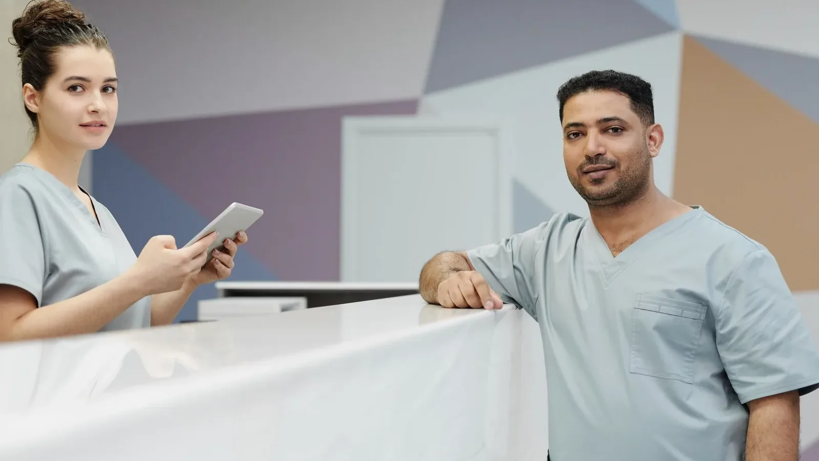 Medical staff members in scrub suits at a modern clinic's reception area.