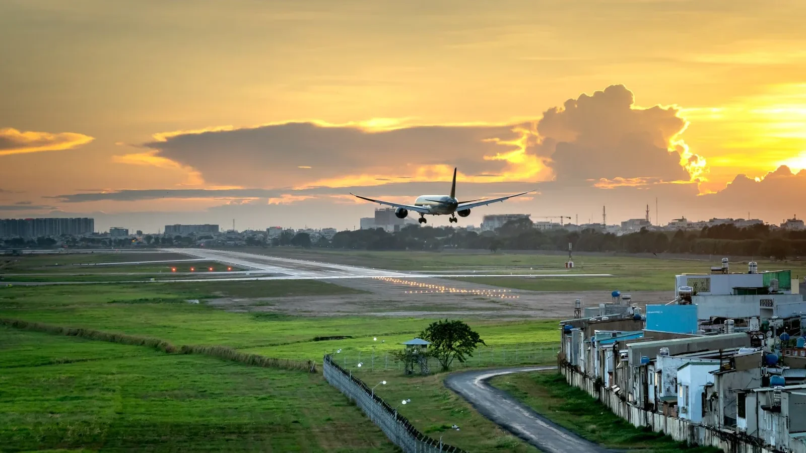 Airplane landing on runway with dramatic sunset sky in background, capturing the golden hour.