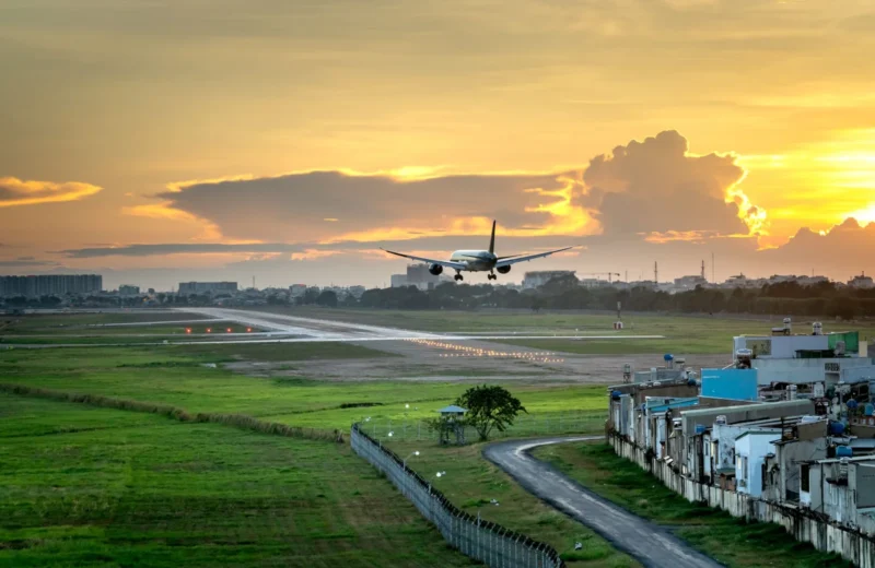 Airplane landing on runway with dramatic sunset sky in background, capturing the golden hour.