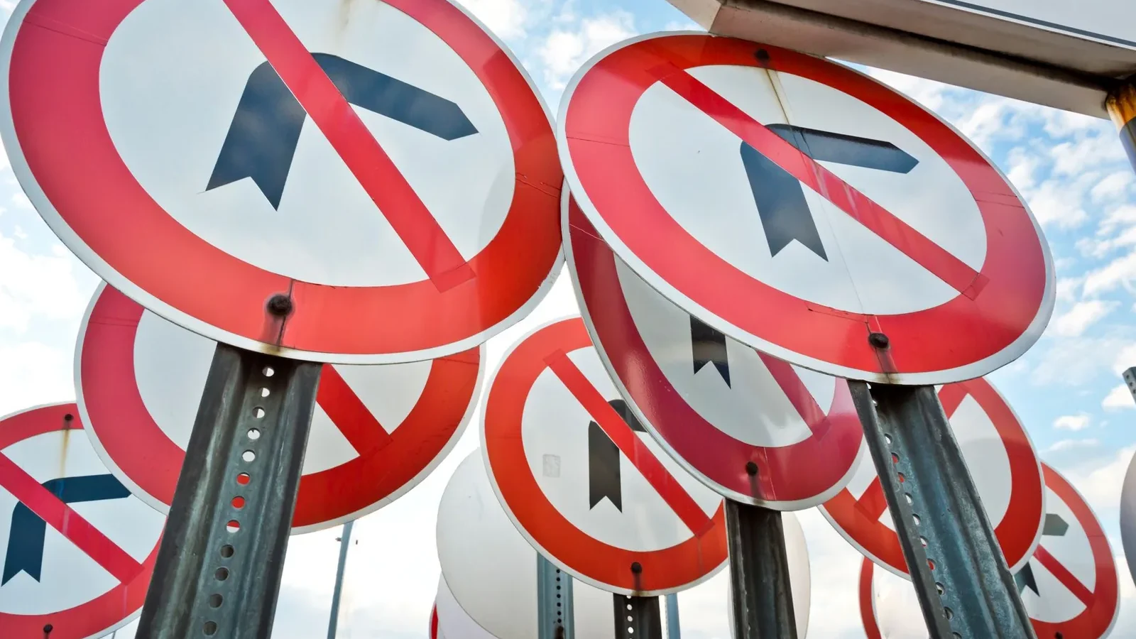 Multiple no left turn traffic signs displayed together under a blue sky.