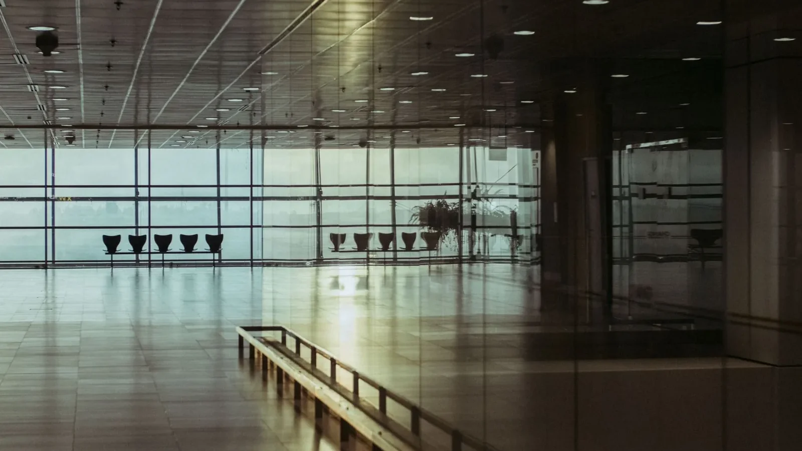 A calm and empty airport terminal in Singapore with a reflective glass facade and soft lighting.