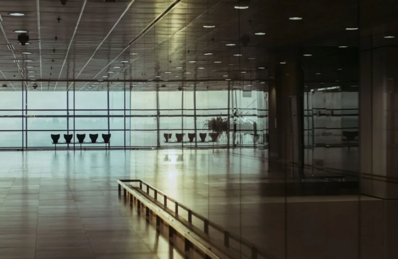 A calm and empty airport terminal in Singapore with a reflective glass facade and soft lighting.
