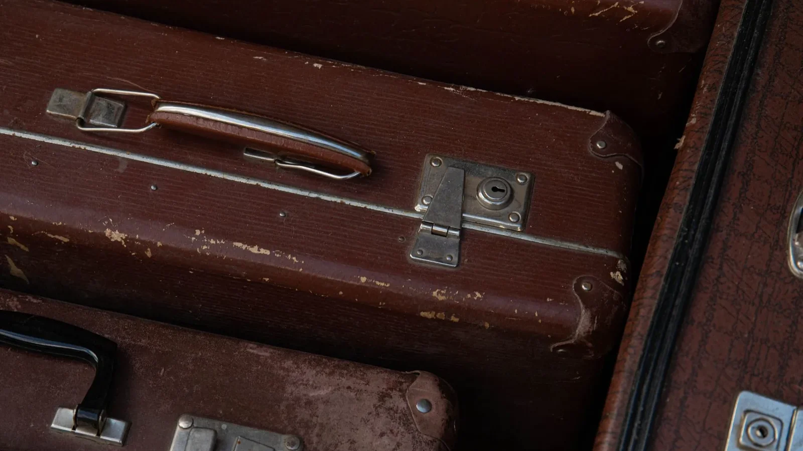 Detailed view of stacked vintage brown suitcases showcasing their classic design and wear.