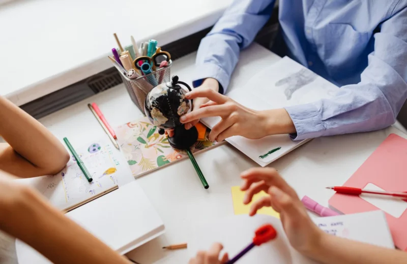 Children engaged in learning with a globe and art supplies on a desk, emphasizing education and creativity.