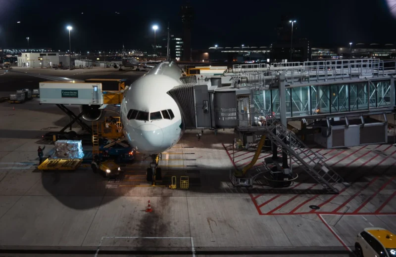 Airplane parked at airport gate during nighttime, unloading cargo and passengers.