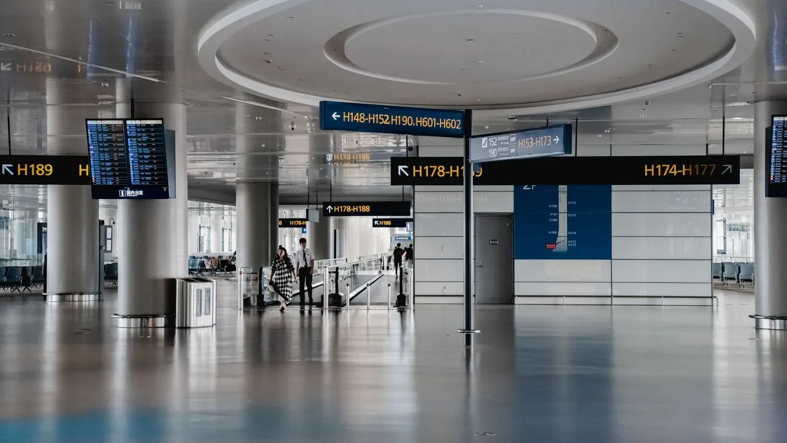 Spacious interior view of a modern airport terminal in Shanghai with signage and travelers.