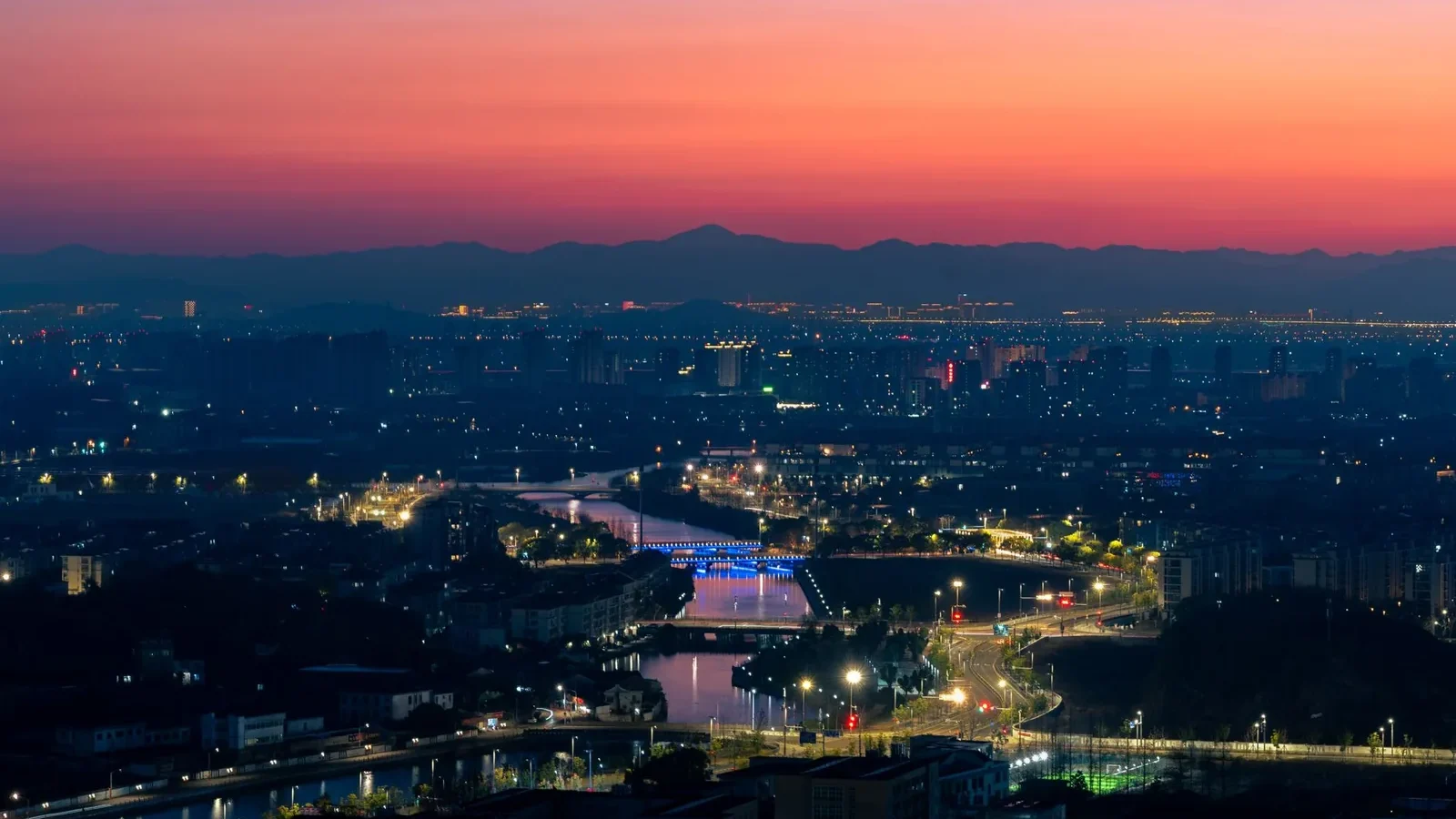A vibrant cityscape at twilight showcasing a glowing skyline and a colorful sunset horizon.