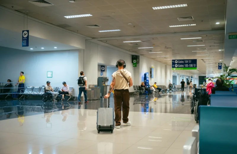 Passengers in a spacious airport terminal, some seated and others walking.