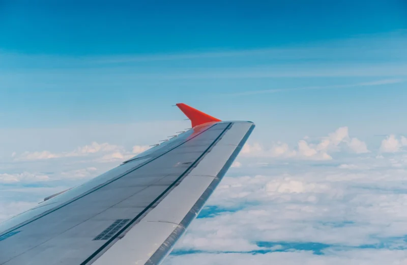 Aerial view from plane showcasing airplane wing above fluffy clouds and blue sky.