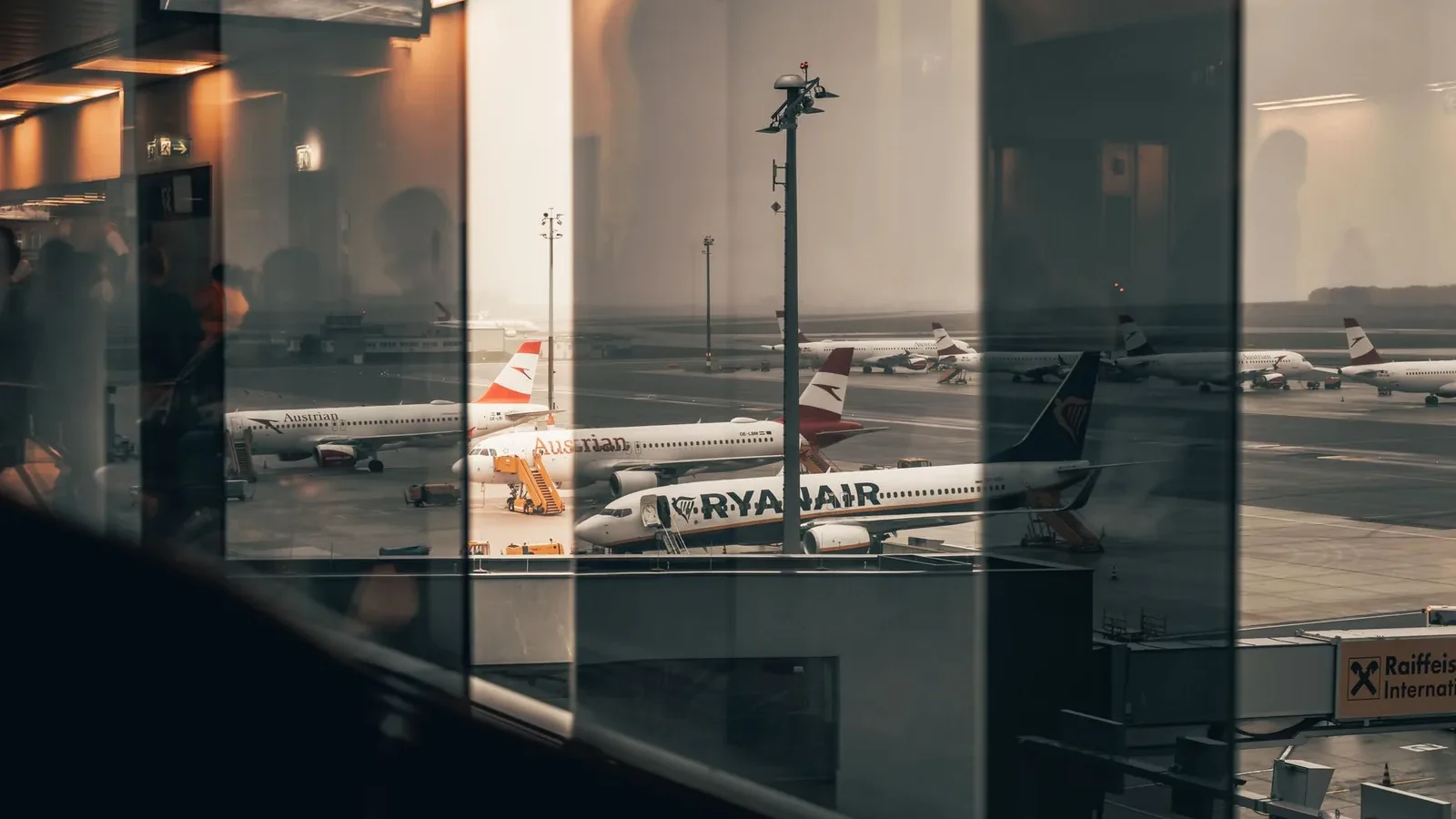 Airplanes at a bustling airport with reflections of interiors in the window panes.