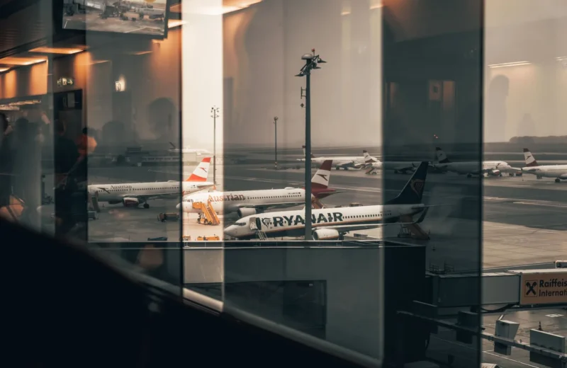 Airplanes at a bustling airport with reflections of interiors in the window panes.