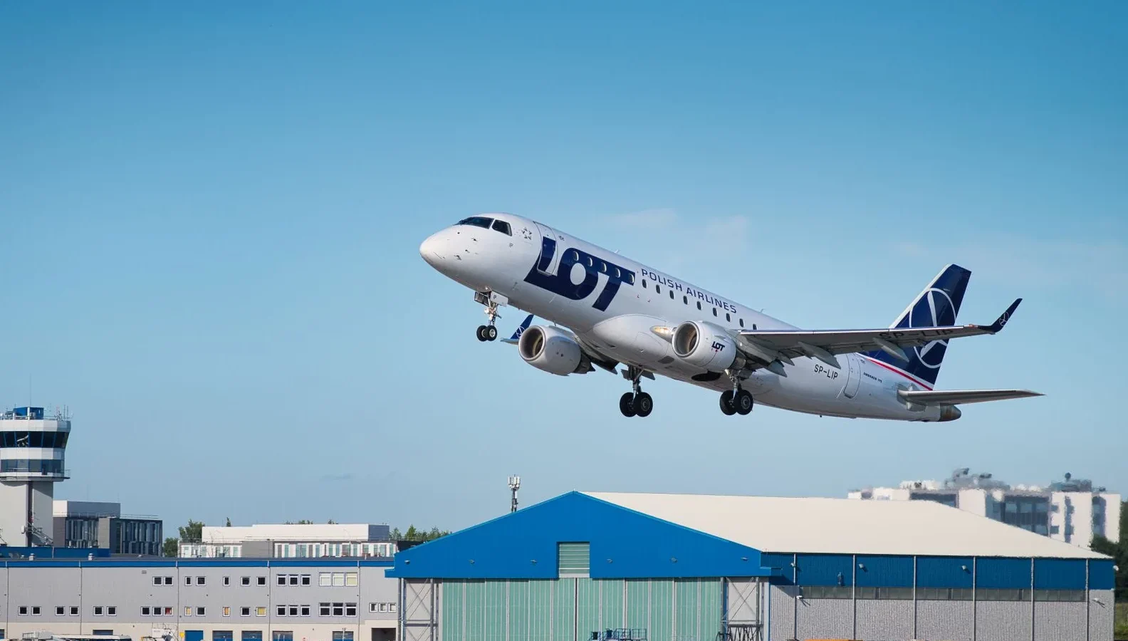 LOT Polish Airlines passenger jet taking off in clear blue skies from airport runway, showcasing aviation scene.