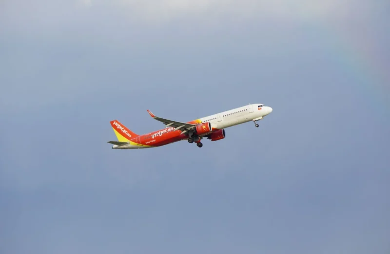 An airplane from the airline VietJet in mid-flight against a clear blue sky.
