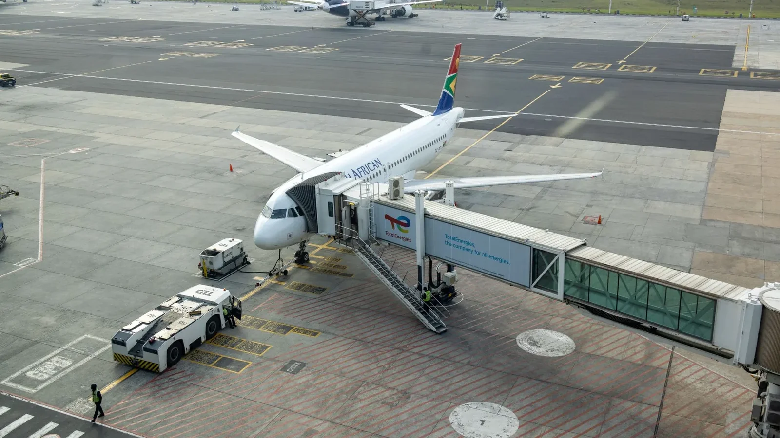 South African Airways plane docked at a gate in an airport, captured from an aerial view.