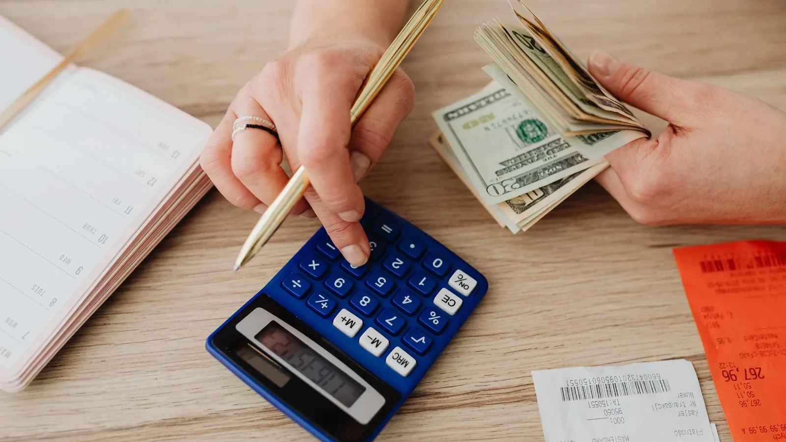 Hands handling cash and calculator for budget planning. Modern financial scene.
