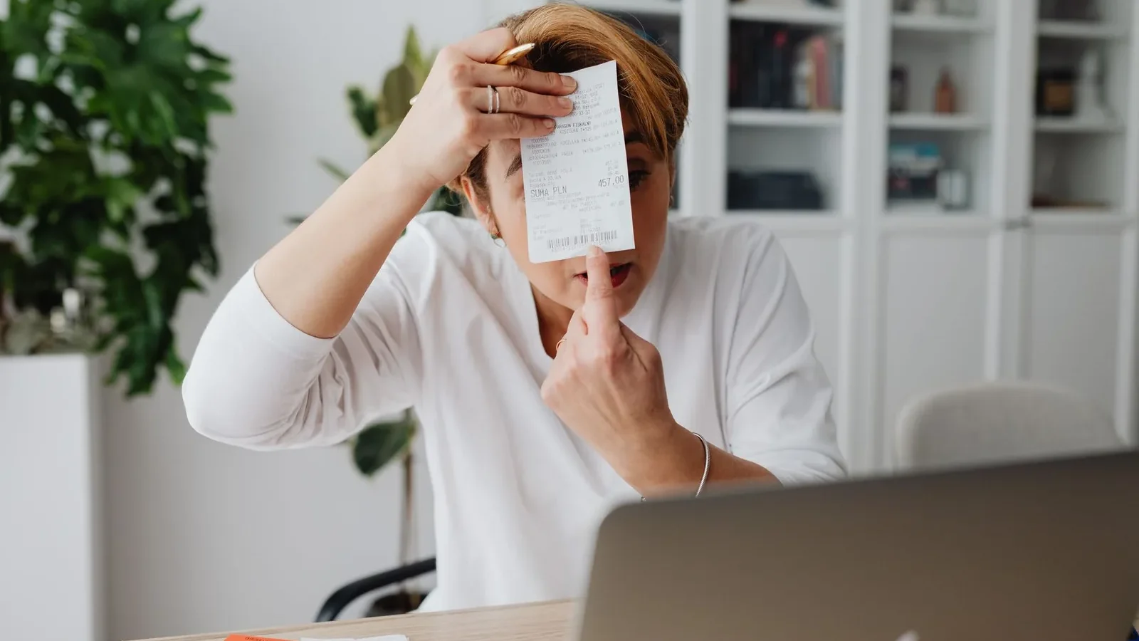 Businesswoman showing a receipt during a home office work session, highlighting technology integration.