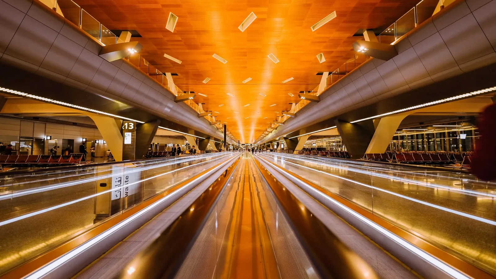 Dramatic long exposure of a modern airport terminal's moving walkalator with architectural ceiling design.